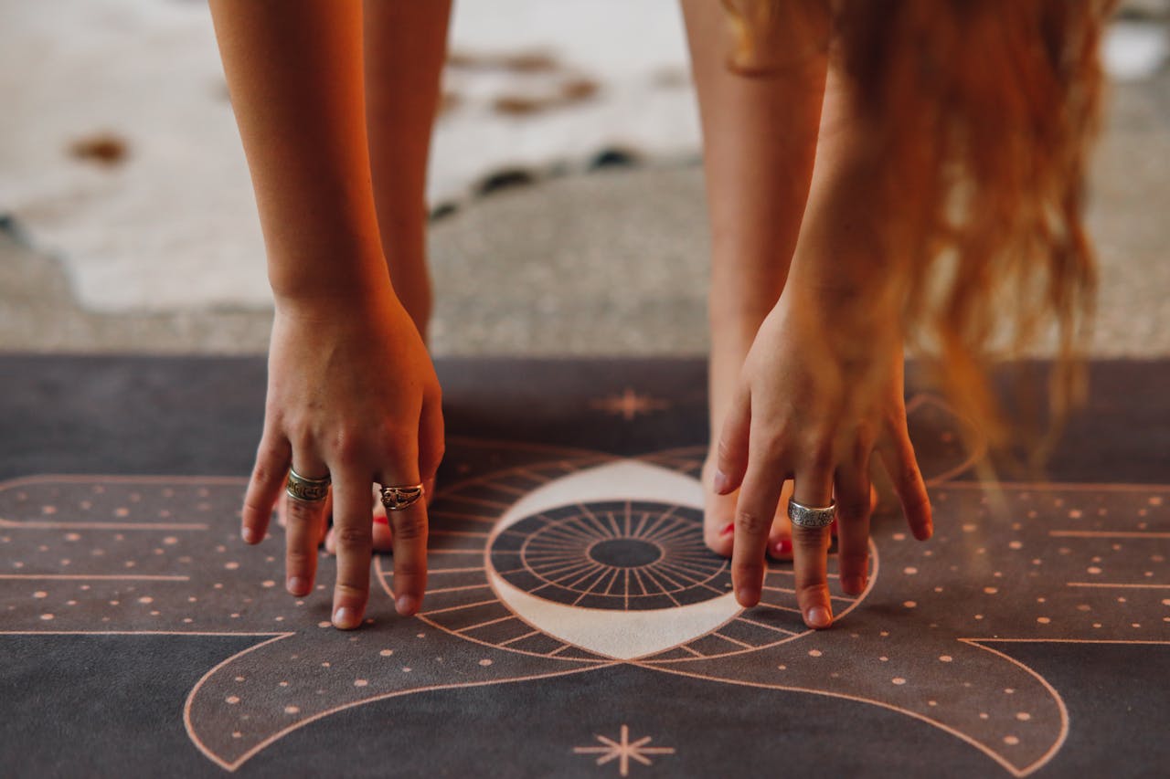 Detailed view of hands with rings in yoga pose on a decorative mat.