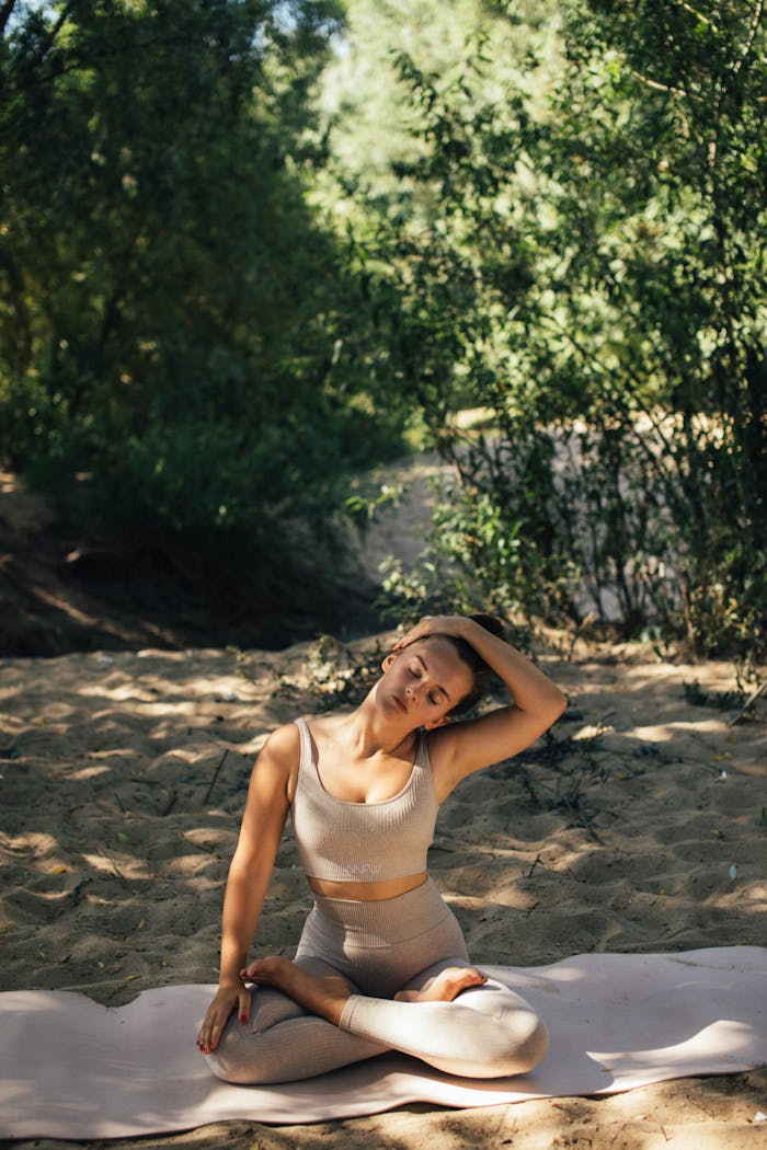Caucasian woman in activewear practicing yoga and stretching in a sunlit forest setting.